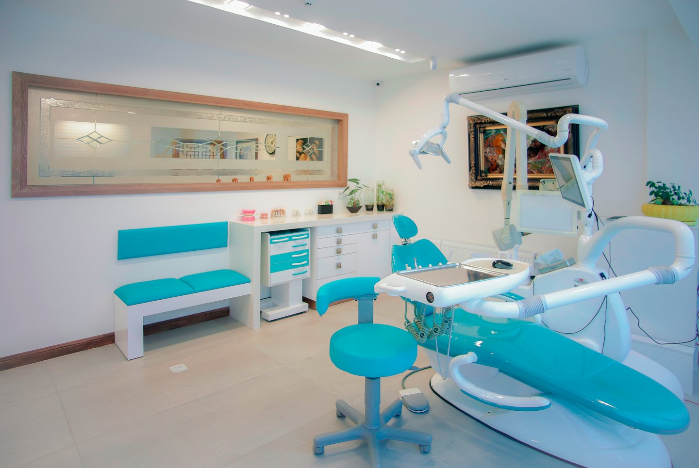 Clínica dental moderna con sillón turquesa y banco de espera.